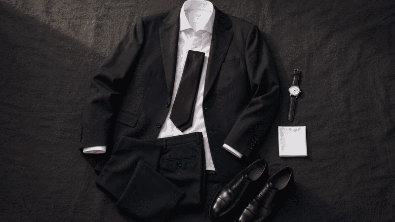 men's corporate interview outfit flat lay with navy suit jacket white dress shirt burgundy tie and black leather oxford shoes