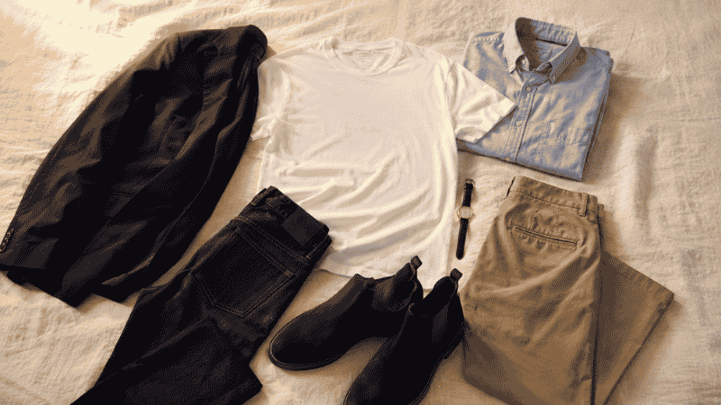 men's first date outfit flat lay showing navy blazer white t-shirt dark jeans oxford shirt chinos and leather chelsea boots for different date venues