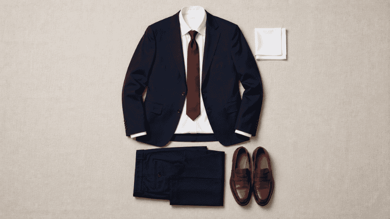 men's cocktail and semi formal wedding outfit flat lay showing navy suit white shirt silk tie and brown leather loafers